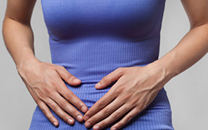 A woman with gastrointestinal problems pressing against her stomach to ease the pain